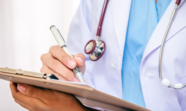 Doctor writing on clipboard chart